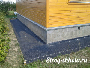 На дно траншеи укладывают гидроизоляционную пленку с нахлестом на дом